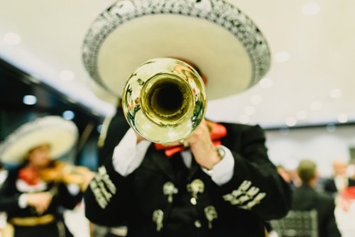 Mariachi vestido con traje tradicional mexicano, tocando la trompeta en una plaza, capturando la esencia de la música folclórica y la cultura mexicana.