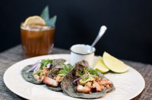 Tres tacos en plato con medio limón y té helado, la combinación perfecta de sabores frescos y auténticos de la cocina mexicana.