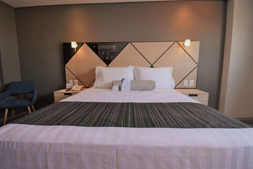 Cama espaciosa con decoración minimalista y ambiente relajante en una habitación del Hotel Kali Ciudadela, perfecta para una estancia cómoda.